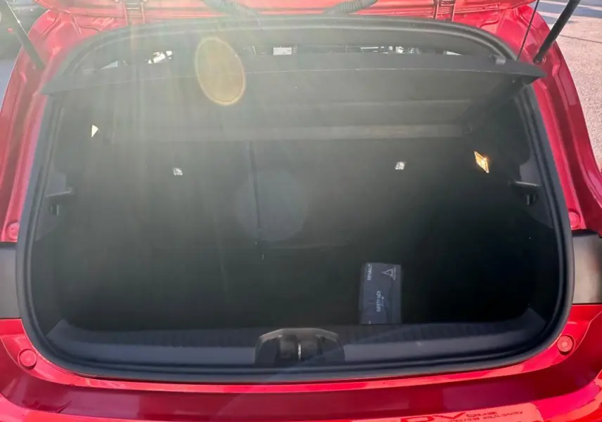 Coffre ouvert d'une Renault Clio rouge foncé 2021, vue arrière, montrant un espace de rangement propre et un kit de sécurité.