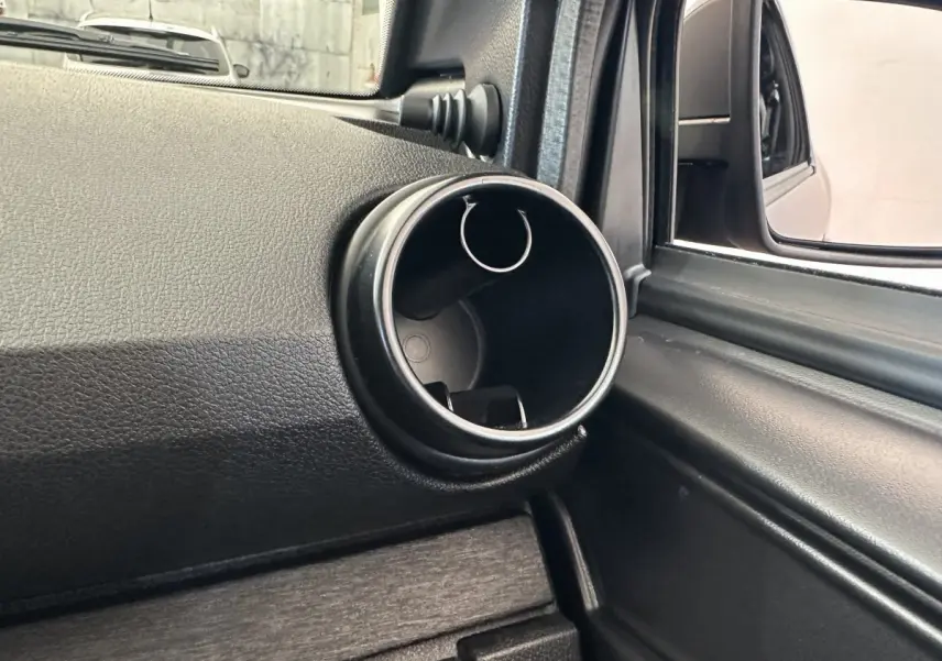 Vue intérieure en gros plan sur la sortie d'air ronde côté conducteur d'une Aixam Ambition gris foncé 2026.