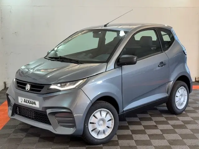 Vue 3/4 avant d'une Aixam Ambition 0.5 City Pack gris foncé avec rétroviseur caméra côté conducteur visible.
