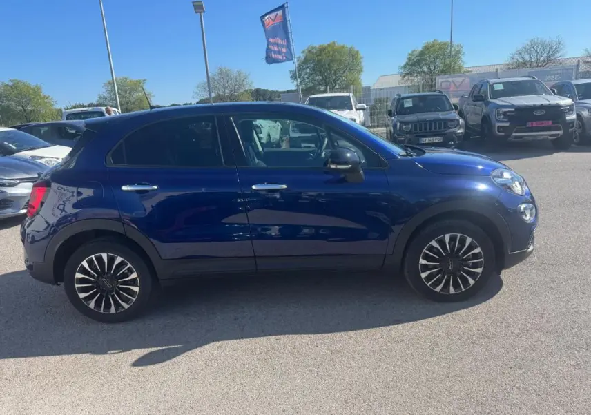 Fiat 500X bleu vue de profil côté gauche, jantes classiques 16 pouces et rétroviseurs noirs brillants.
