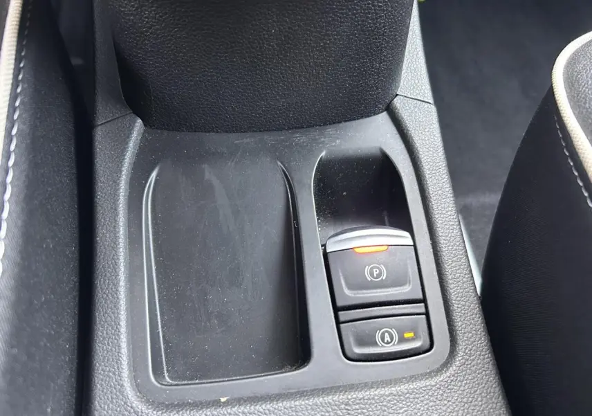Gros plan sur la console centrale noire avec boutons frein de parking et aide au démarrage Renault Clio 2025.