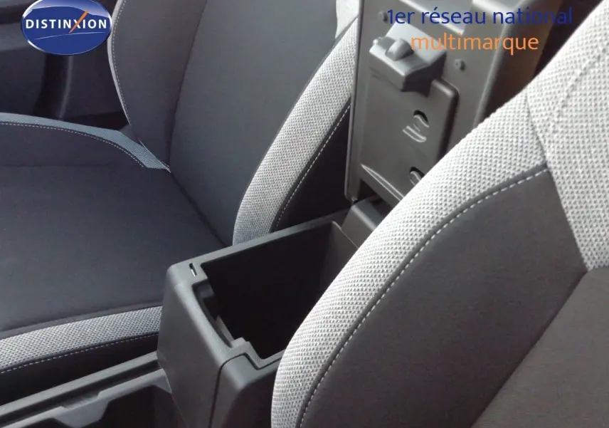 Détail de l’intérieur montrant l’accoudoir central ouvert et les sièges tissu gris clair et noir du Dacia Duster 2026.