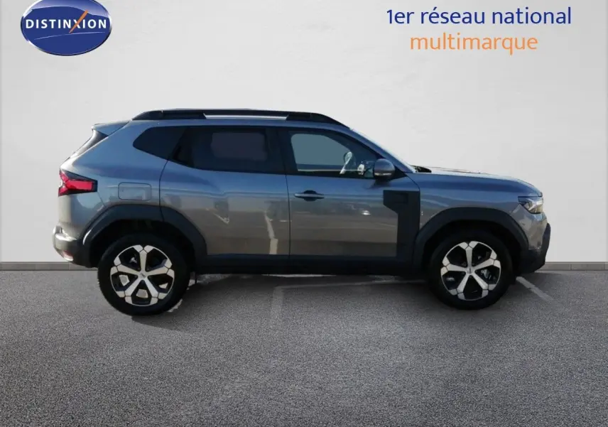 Vue de profil côté gauche d’un Dacia Duster gris schiste métal 2026 avec jantes bi-ton et vitres teintées.