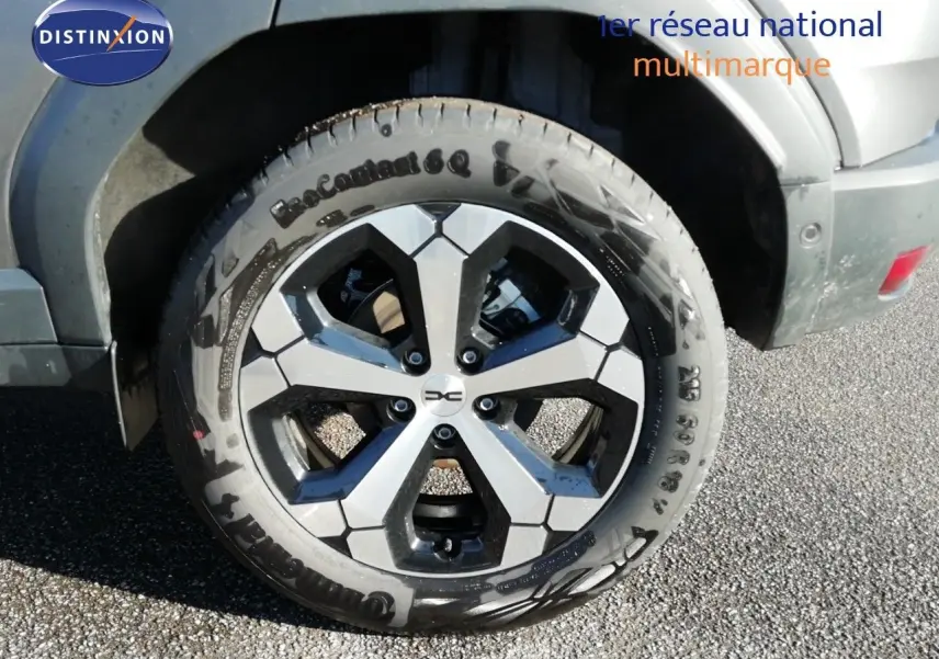 Gros plan sur la roue avant droite du Dacia Duster gris schiste métal avec jante alliage bi-ton distinctive.