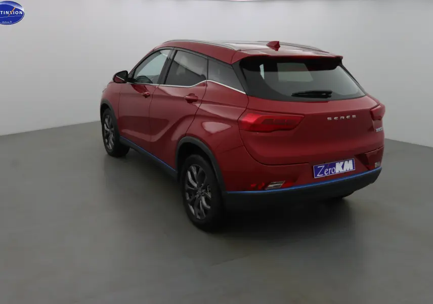 Vue 3/4 arrière droite d'un SUV électrique SERES 3 rouge solaire métallisé avec toit panoramique et jantes foncées.