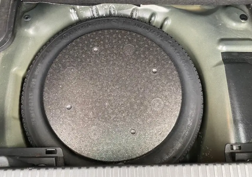 Vue plongeante sur la roue de secours galette dans le coffre d'un Citroën C3 Aircross noir 2019.