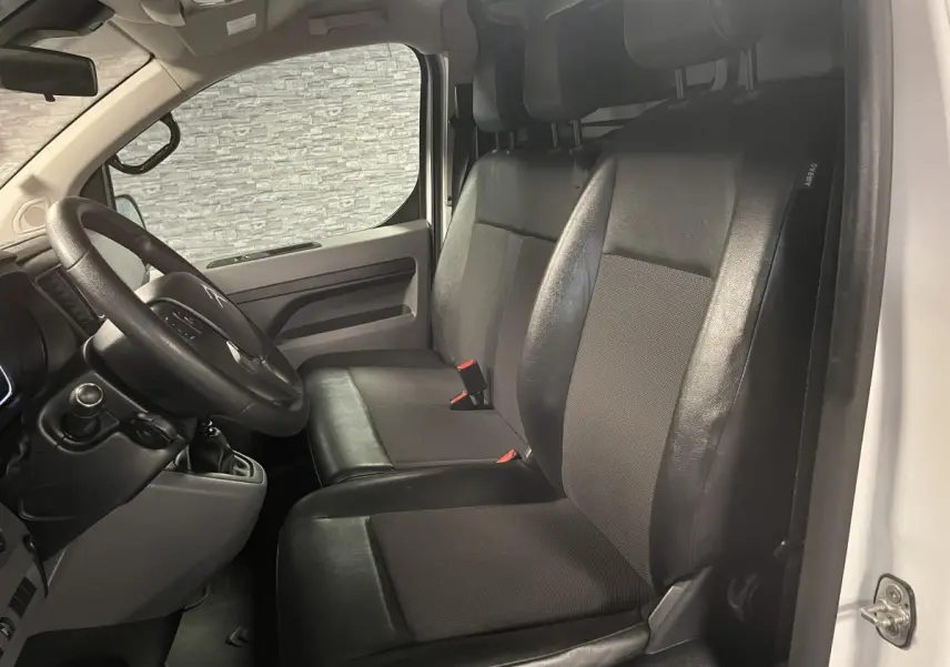 Vue intérieure côté conducteur du Citroën Jumpy blanc 2019 avec sièges mixtes TEP/tissu et volant noir.