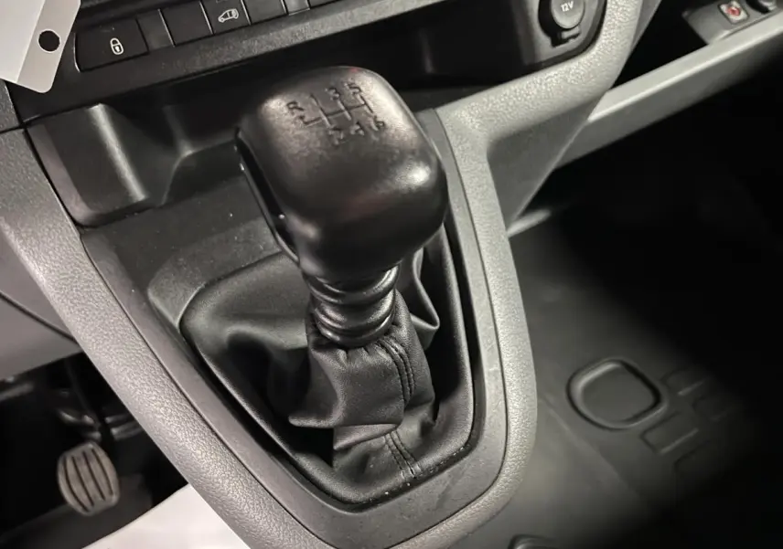 Gros plan sur levier de vitesses manuel noir dans l'habitacle gris du Citroën Jumpy blanc de 2019.
