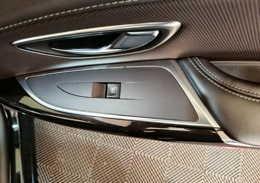 Gros plan sur la poignée intérieure et commande de vitre côté gauche du Renault Espace noir, finition cuir et chrome.