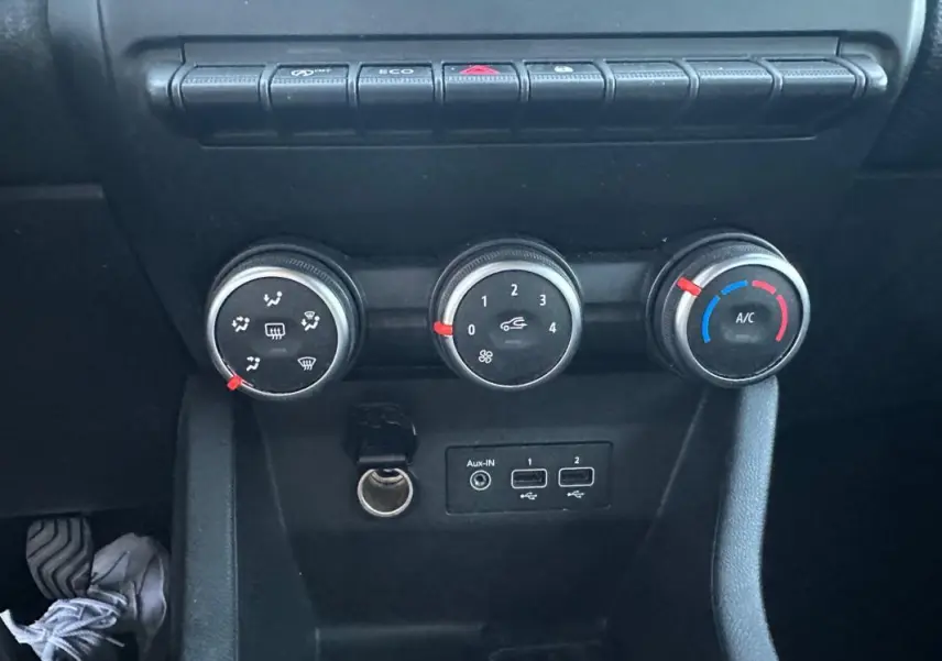 Vue rapprochée des commandes de climatisation manuelle et des ports USB dans une Renault Clio gris foncé 2022.