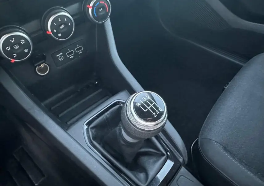 Gros plan sur le levier de vitesses manuel et la console centrale noire de la Renault Clio gris foncé 2022.