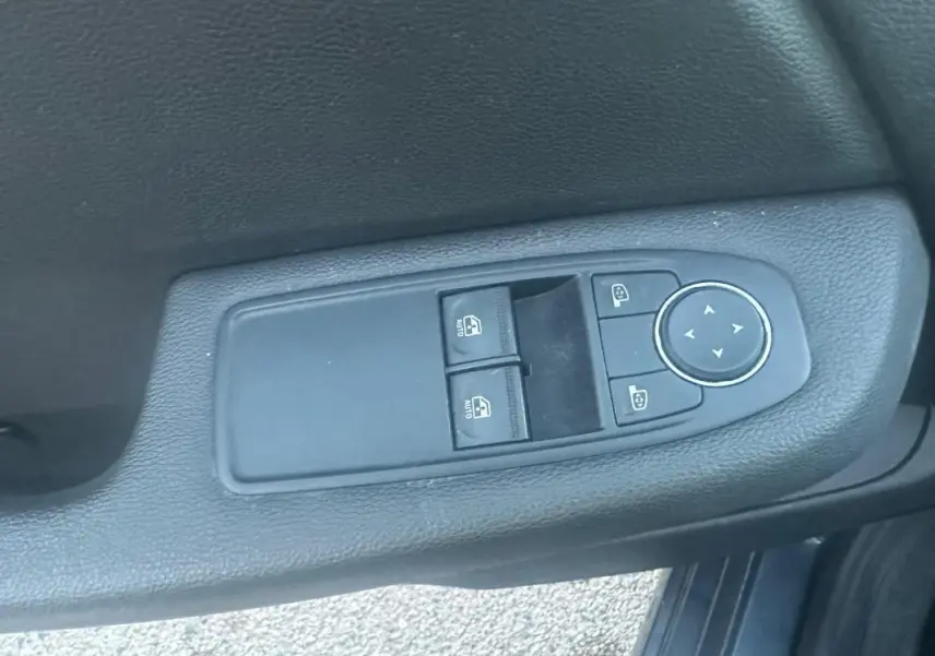 Commande des vitres électriques et réglage des rétroviseurs sur la porte côté gauche d'une Renault Clio gris foncé.