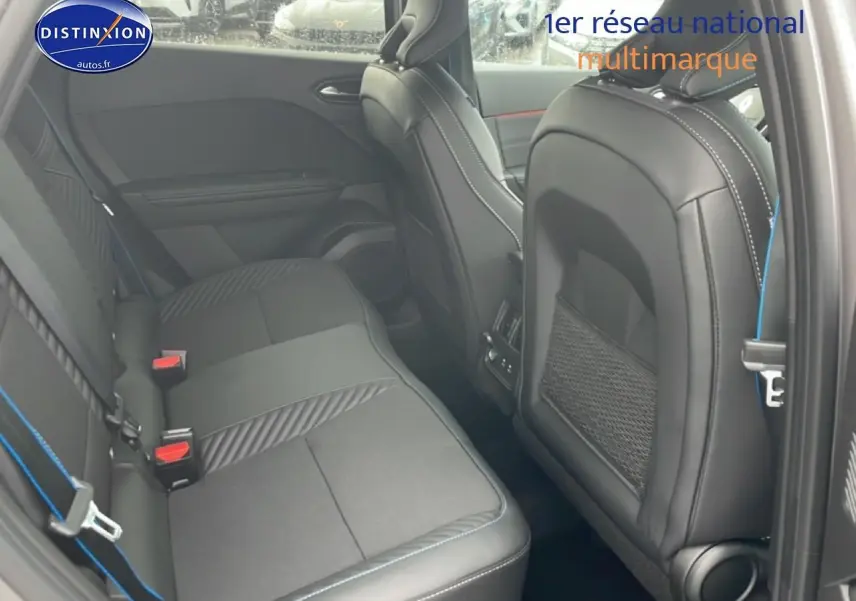 Vue intérieure arrière côté gauche du Renault Captur gris cassiopée, sièges noirs avec surpiqûres bleues et rangements filet au dos des sièges avant.