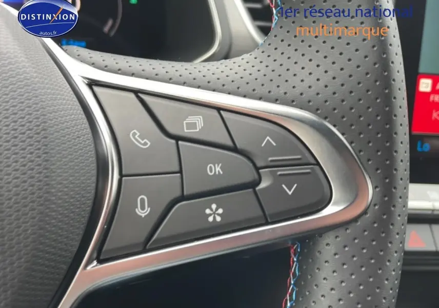 Gros plan sur les commandes multifonctions côté gauche du volant cuir perforé du Renault Captur gris cassiopée.