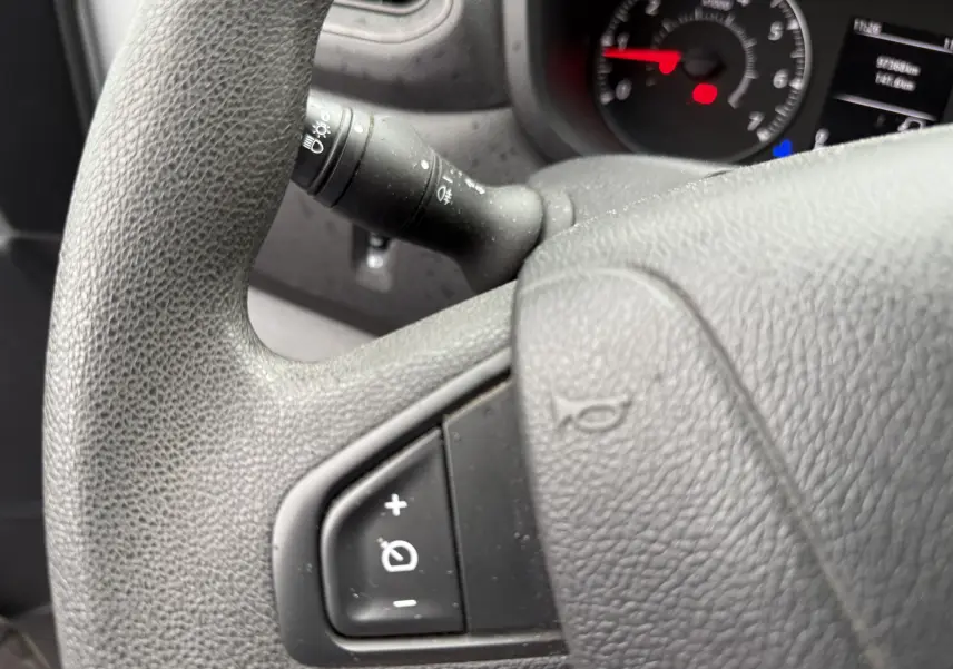 Gros plan sur le volant noir du Nissan NV400 Fourgon avec commandes de régulateur de vitesse visibles.