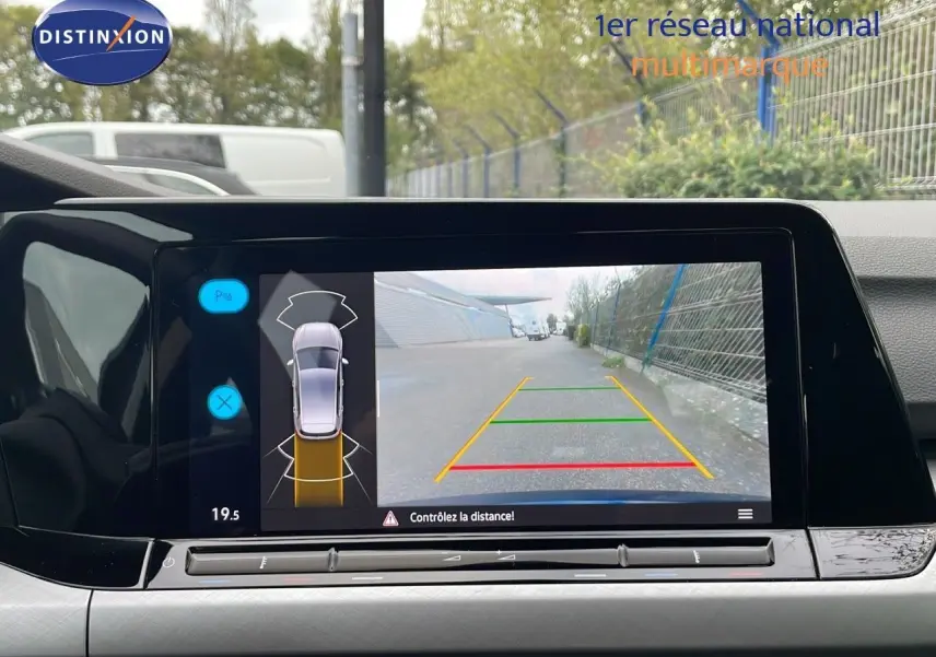 Vue de l'écran multimédia affichant la caméra de recul d'une Volkswagen Golf VIII bleu lapiz metal en stationnement.