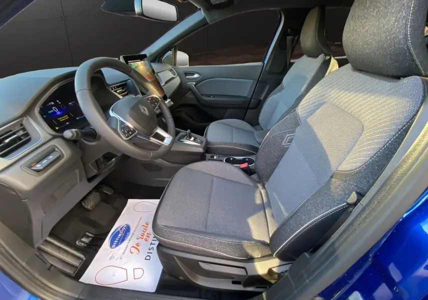 Vue intérieure côté conducteur du Renault Captur 2025 bleu Iron, mettant en valeur les sièges tissu gris et le tableau de bord moderne.