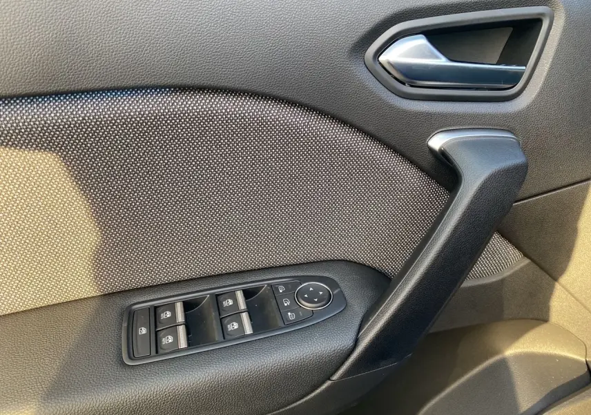 Gros plan sur la porte intérieure côté gauche du Renault Captur 2025, montrant les commandes de vitres et la poignée noire.