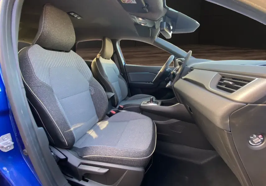 Vue intérieure côté gauche du Renault Captur 2025 bleu Iron avec sièges tissu gris et tableau de bord épuré.