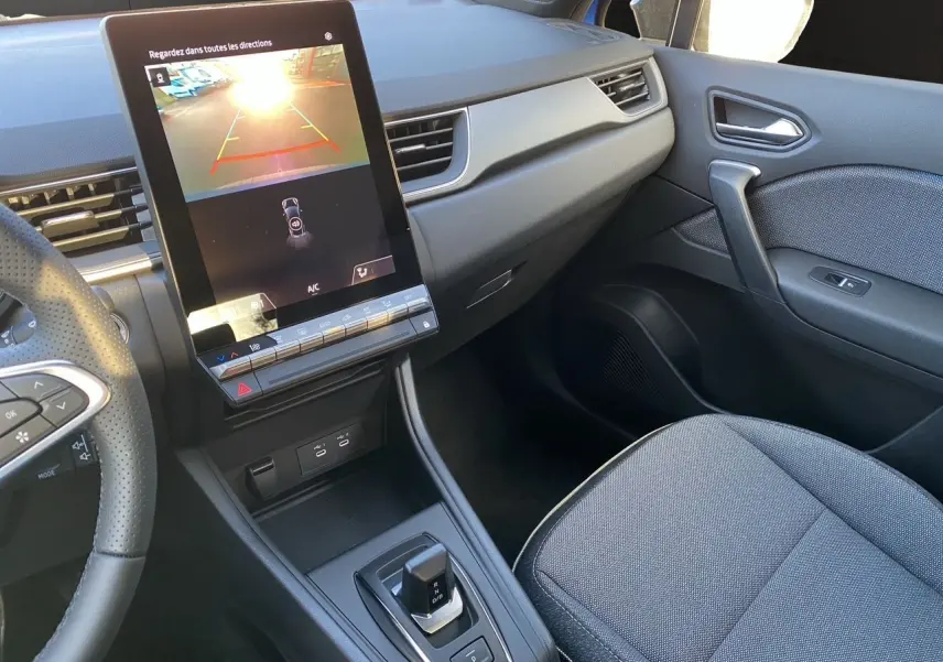 Vue intérieure du tableau de bord et console centrale du Renault Captur 2025 avec écran tactile et levier de boîte automatique.