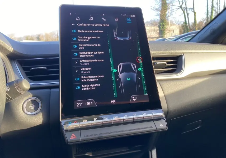 Vue intérieure centrée sur l'écran tactile du tableau de bord du Renault Captur 2025, affichant les aides à la conduite.