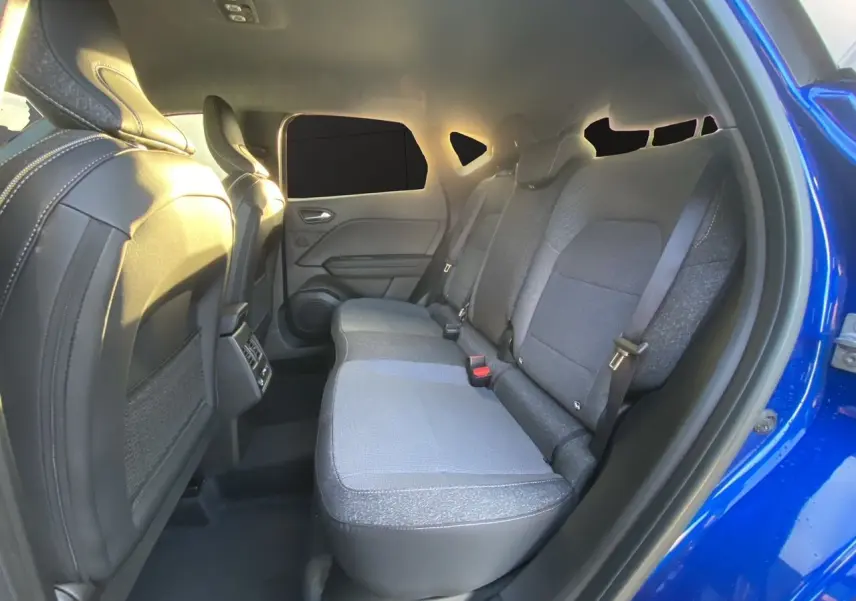 Vue intérieure arrière côté droit du Renault Captur 2025 bleu Iron avec sièges tissu et garnitures noires.