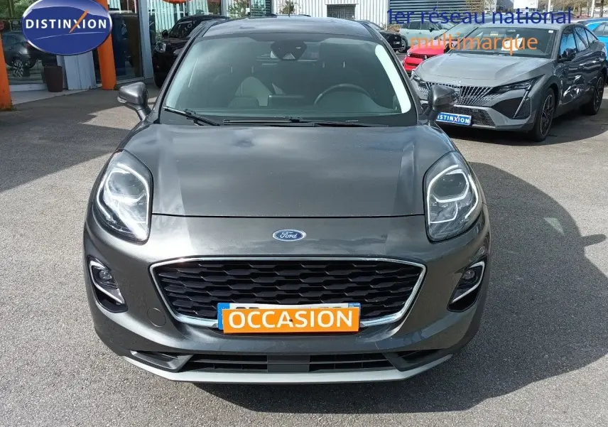 Vue avant d'une Ford Puma gris foncé métal avec calandre noire et plaque "OCCASION" orange visible.