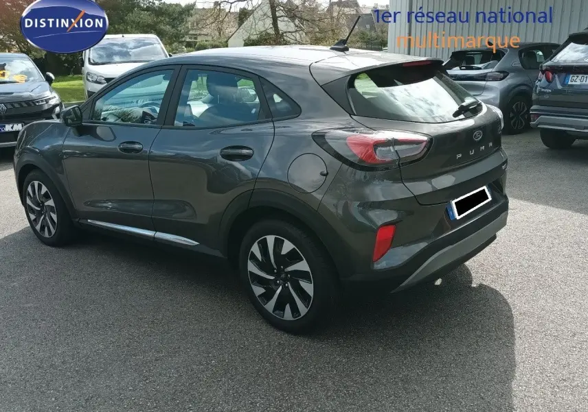 Ford Puma gris foncé métal vu en 3/4 arrière droit, mettant en valeur ses feux arrière et ses jantes bicolores.