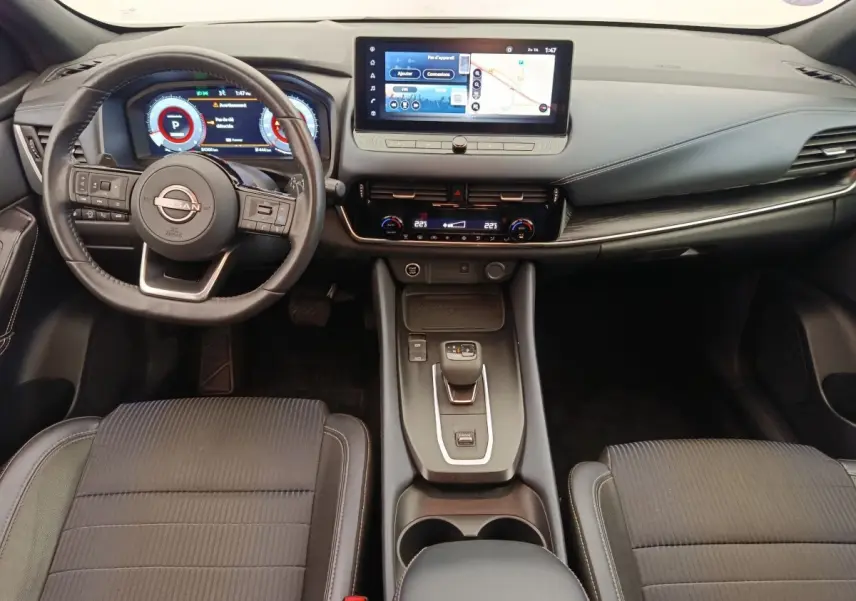 Vue intérieure avant du Nissan Qashqai Tekna 2023 noir, tableau de bord avec écran tactile 12,3 pouces et volant cuir multifonctions.