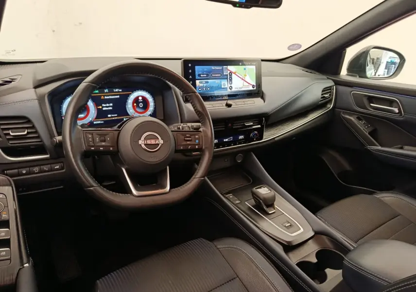 Intérieur noir du Nissan Qashqai 2023, vue du poste de conduite avec volant cuir et écran tactile central.