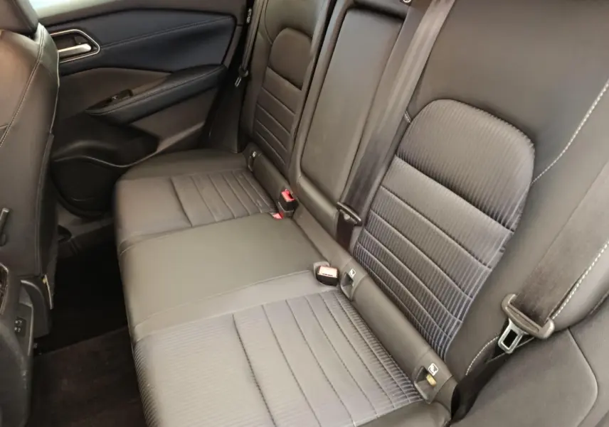 Vue intérieure côté gauche de la banquette arrière noire du Nissan Qashqai 1.3 MHEV Tekna 2023 avec ceintures de sécurité visibles.