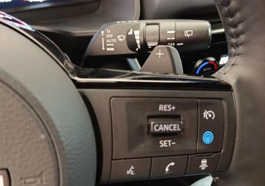 Gros plan sur les commandes au volant côté droit du Nissan Qashqai noir 2023, avec régulateur de vitesse et palettes de changement.