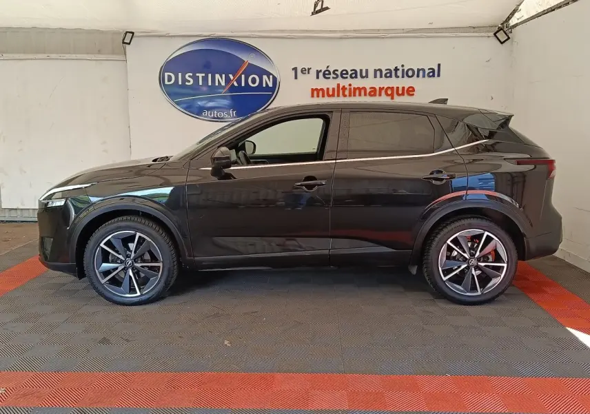 Nissan Qashqai noir vue de profil côté gauche, avec jantes alliage et toit noir brillant dans un showroom.