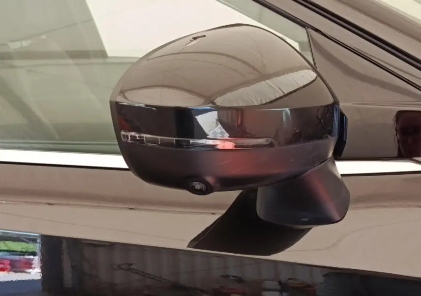 Rétroviseur côté gauche noir brillant du Nissan Qashqai 2023 avec clignotant intégré et caméra de surveillance.