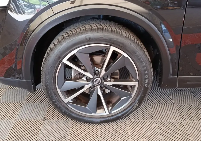 Gros plan sur la roue avant gauche noire du Nissan Qashqai 2023 avec jante alliage bicolore et pneu Firestone.