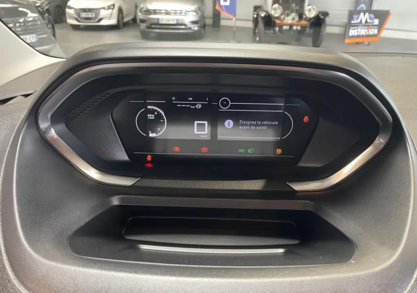 Vue rapprochée du tableau de bord numérique du Peugeot Partner 2026 affichant des alertes et informations de conduite.