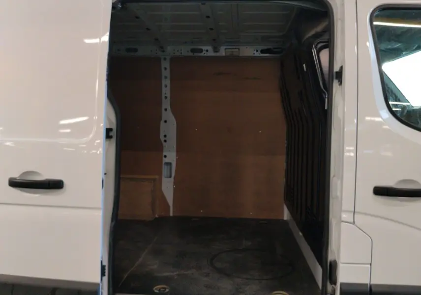 Vue de côté droit sur l’ouverture de la porte coulissante d’un Renault Master blanc 2023, montrant l’espace de chargement vide.
