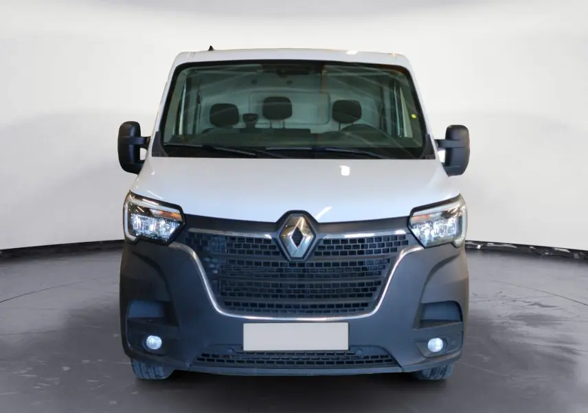 Vue frontale d’un Renault Master blanc 2023 avec calandre noire et feux allumés sur fond neutre.