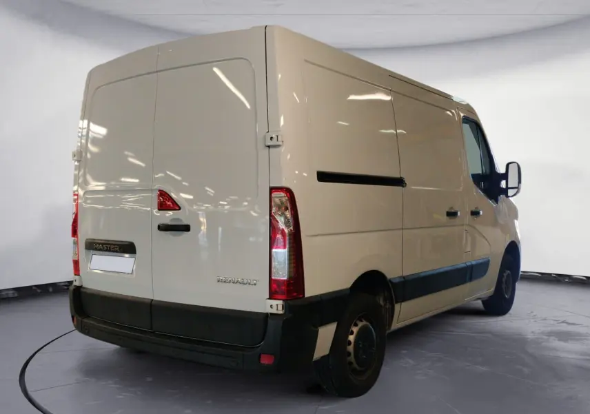 Vue 3/4 arrière droite d’un utilitaire Renault Master blanc, avec portes arrière fermées et protections noires sur les bas de caisse.