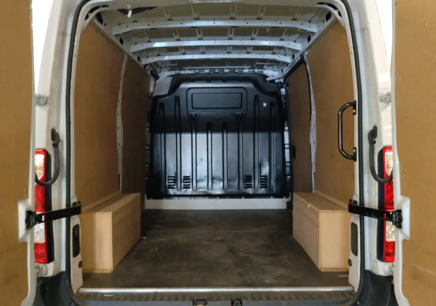 Vue arrière ouverte du Renault Master blanc 2023, montrant l’espace de chargement avec habillage bois et cloison noire.
