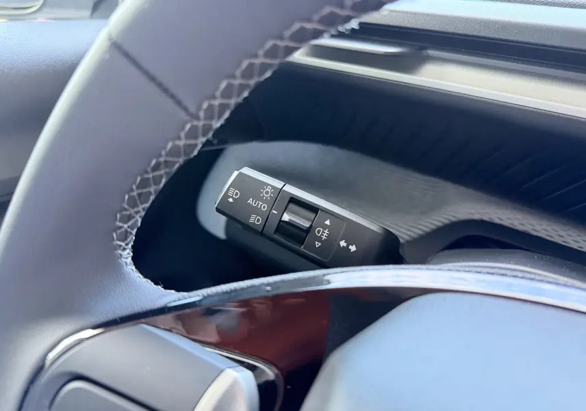 Gros plan sur la commande des feux au volant du Citroën E-C3 113 MAX 2025, intérieur noir et gris.