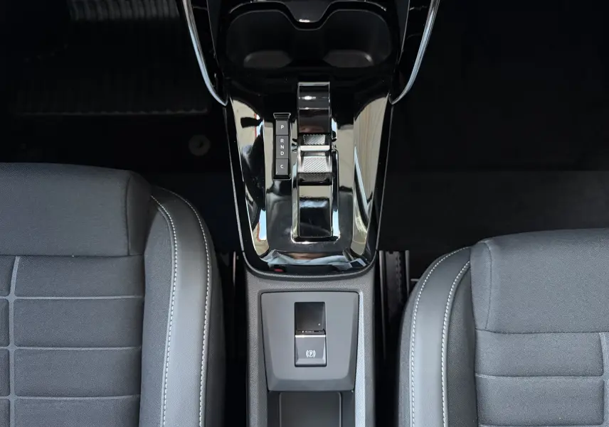Vue plongeante sur la console centrale noire brillante et la sellerie tissu noir de la Citroën E-C3 113 MAX 2025.