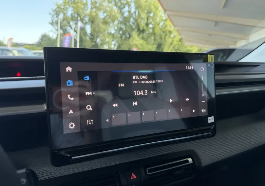 Écran tactile central du tableau de bord de la Citroën E-C3 113 MAX 2025, affichant la radio FM sur fond intérieur gris.