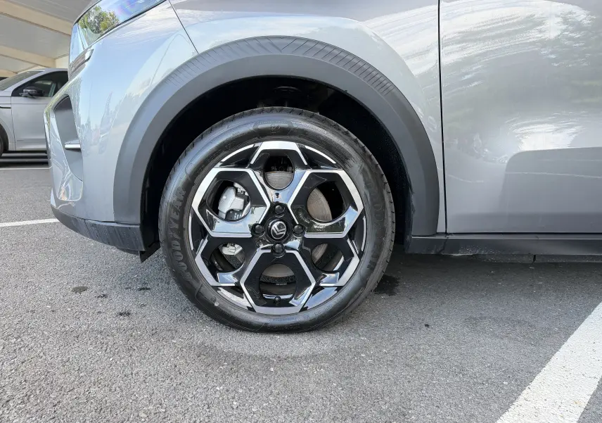Gros plan sur la roue avant gauche et la carrosserie gris Mercury d'une Citroën E-C3 113 MAX avec jante alliage 17 pouces.