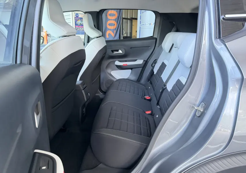 Vue intérieure côté arrière droit de la banquette arrière en tissu noir et clair d'une Citroën E-C3 113 MAX gris Mercury 2025.