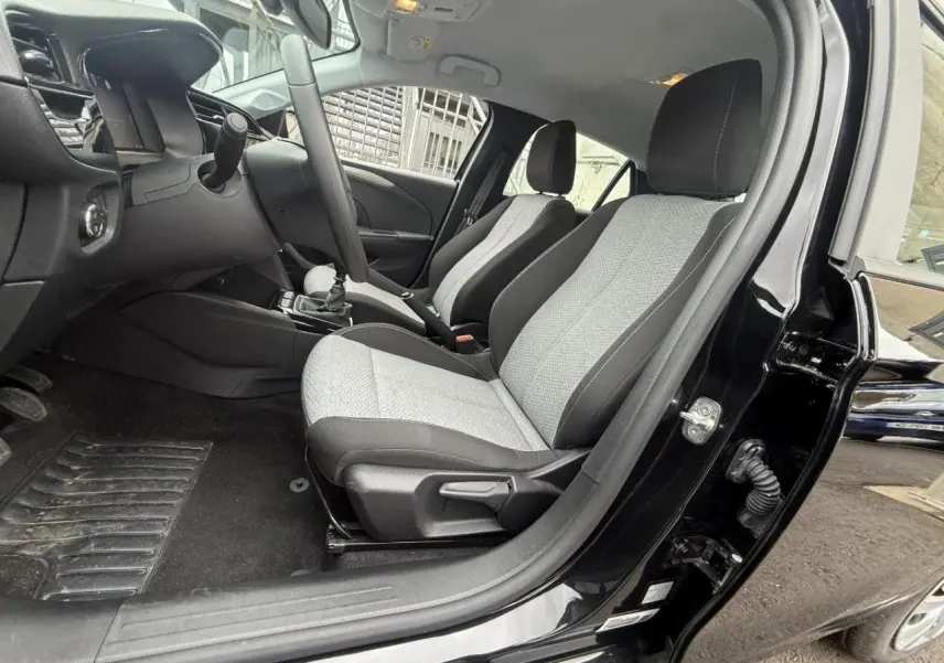 Vue intérieure côté conducteur de l’Opel Corsa 2025 noir karbon, montrant les sièges tissu bicolore et la boîte manuelle.