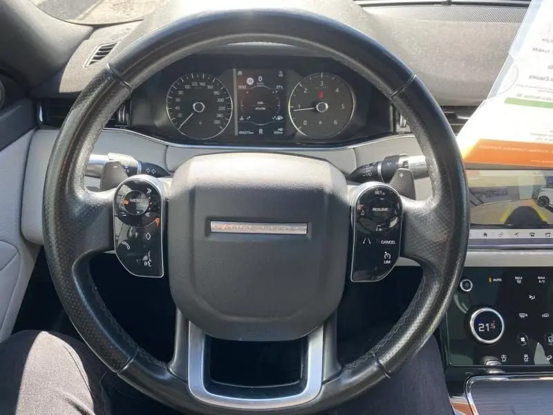 Vue rapprochée du volant noir perforé du Range Rover Evoque 2019 avec tableau de bord digital et commandes intégrées.