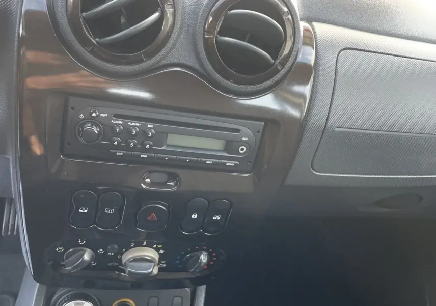 Intérieur du tableau de bord gris foncé du Dacia Duster 2011, avec commandes de climatisation et levier de vitesses manuel visible.