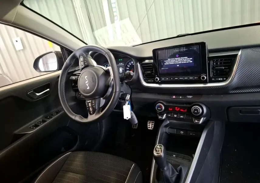 Intérieur du Kia Stonic 2024 gris météore, vue côté conducteur, volant multifonction et boîte manuelle visible.