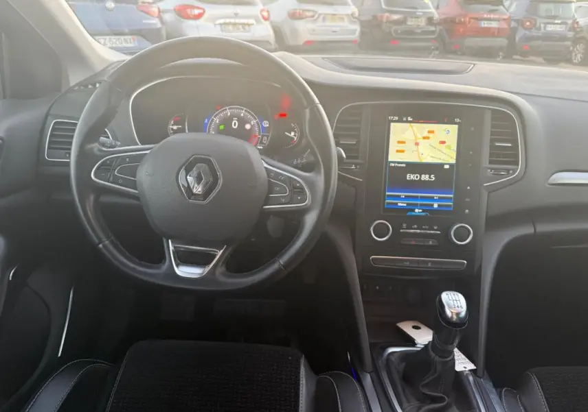 Vue intérieure centrée sur le volant cuir et la console centrale avec écran tactile d'une Renault Mégane IV gris clair de 2016.